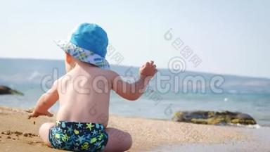 小男孩<strong>在海滩上</strong>潮湿的沙滩<strong>上玩耍</strong>。 他学会爬行，波浪拥抱他。